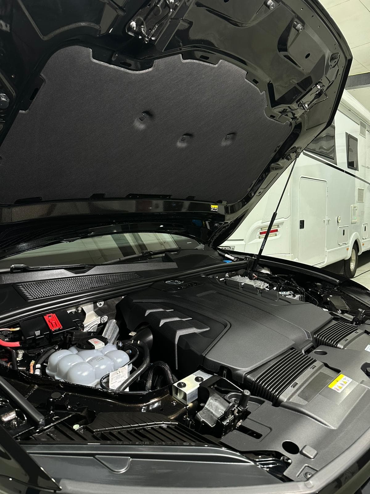 Motorraum eines dunklen Autos, Haube offen
