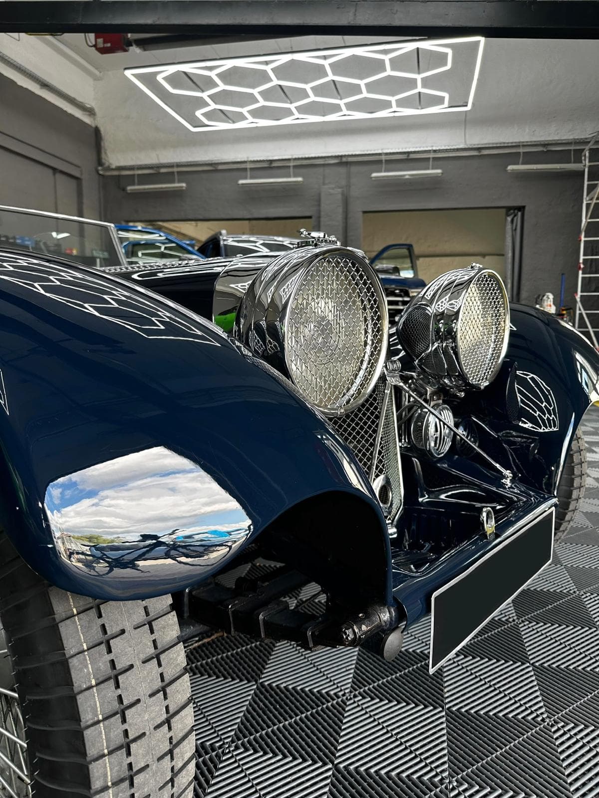 Spiegelnder Kotflügel und verchromte Scheinwerfer mit Schutzgittern an einem klassischen Jaguar