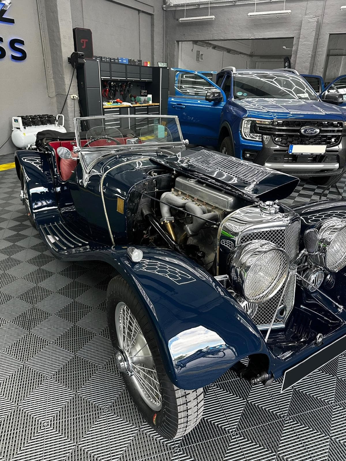 Klassischer Jaguar-Roadster mit geöffneter Motorhaube und rotem Leder in unserer Halle
